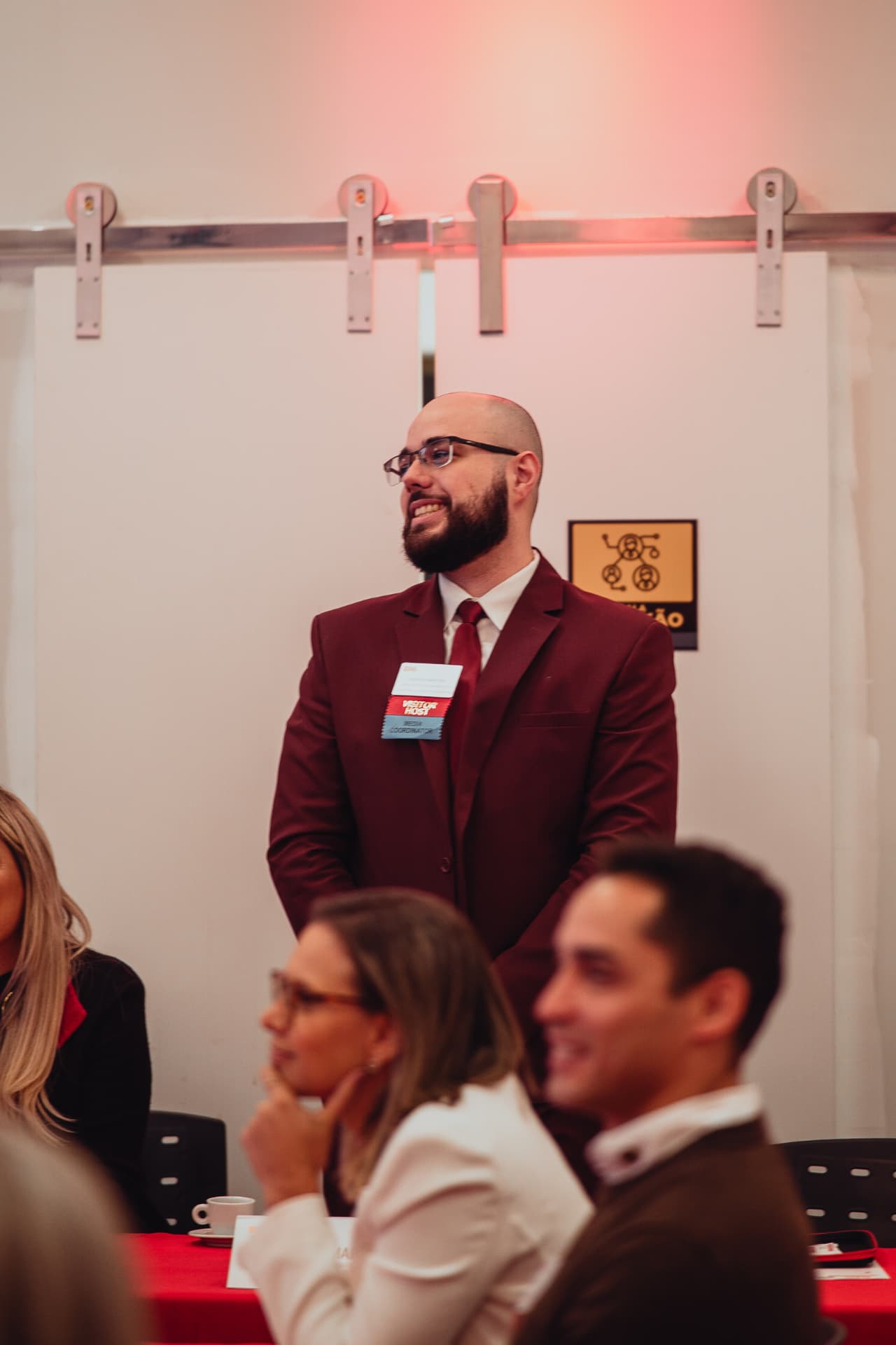 Sergio Martins sorrindo em um evento do BNI, vestindo terno vinho